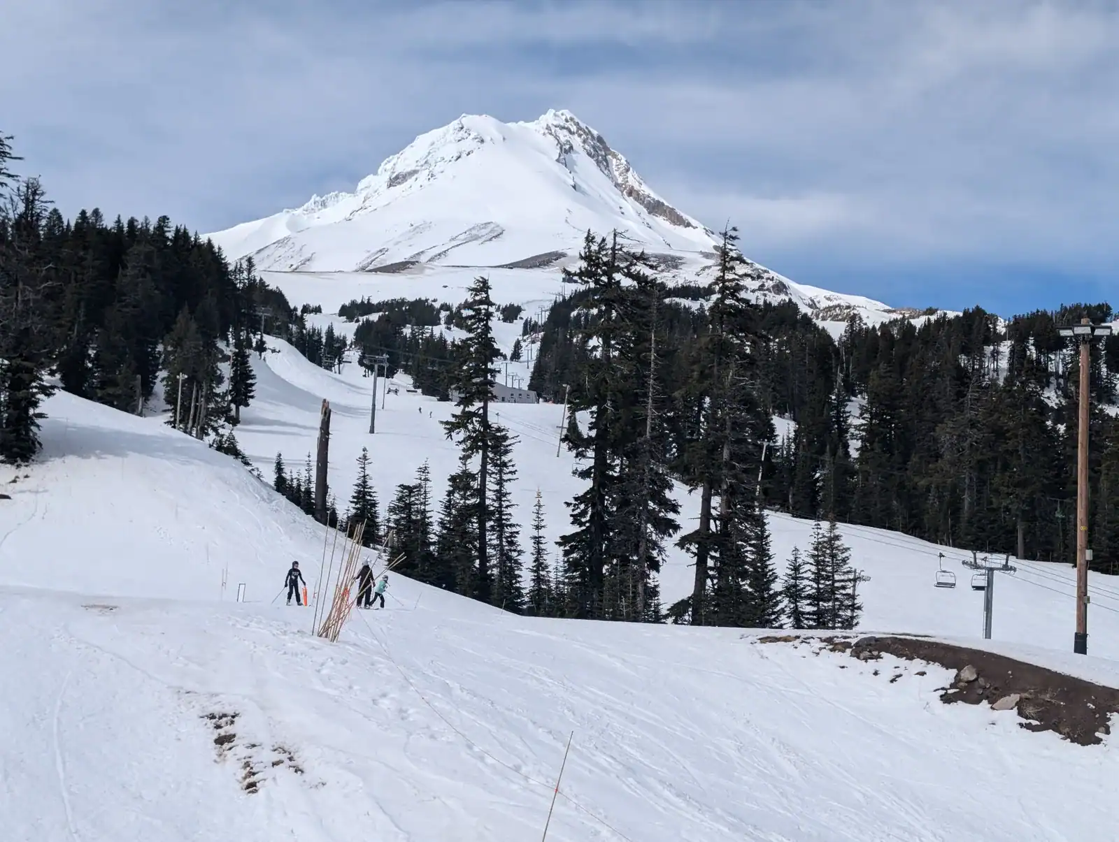 Snow-covered Mount Hood above evergreen trees, ski runs, and chairlifts.