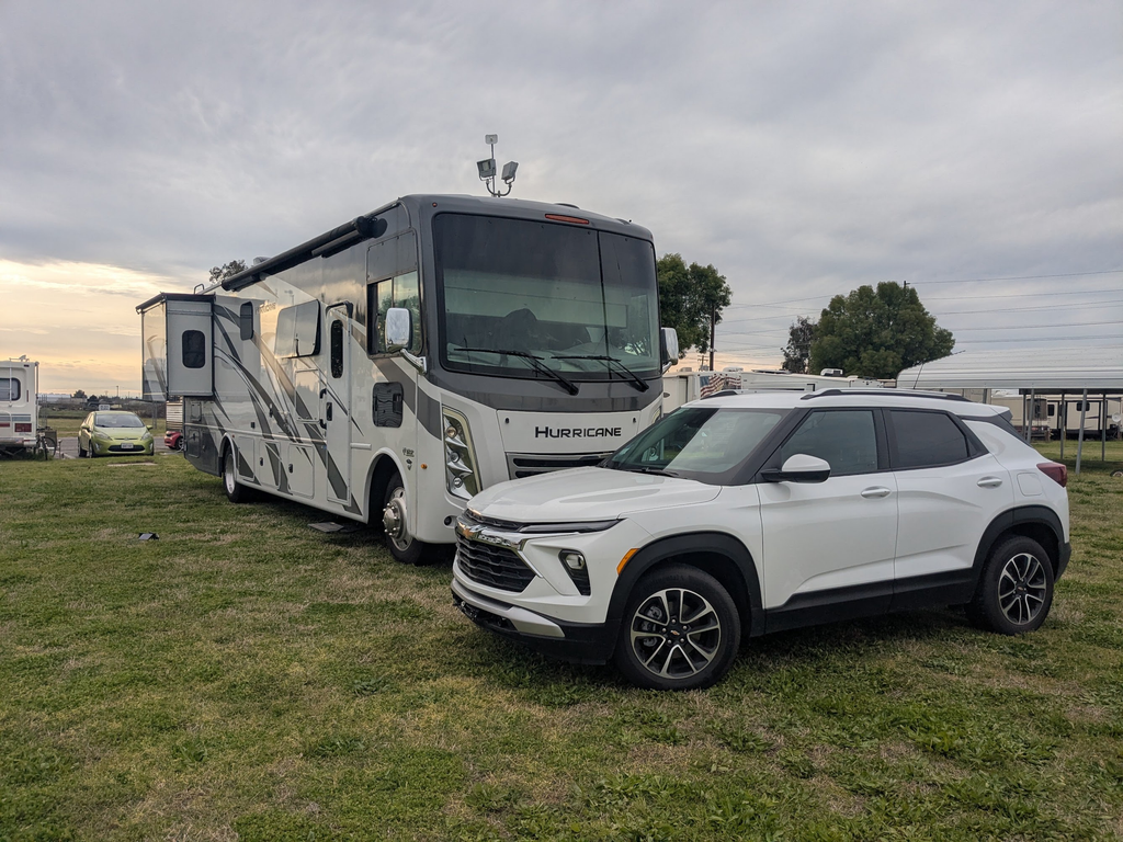 Earl Grey, our gray Thor Hurricane motorhome, parked on grass beside a white SUV.